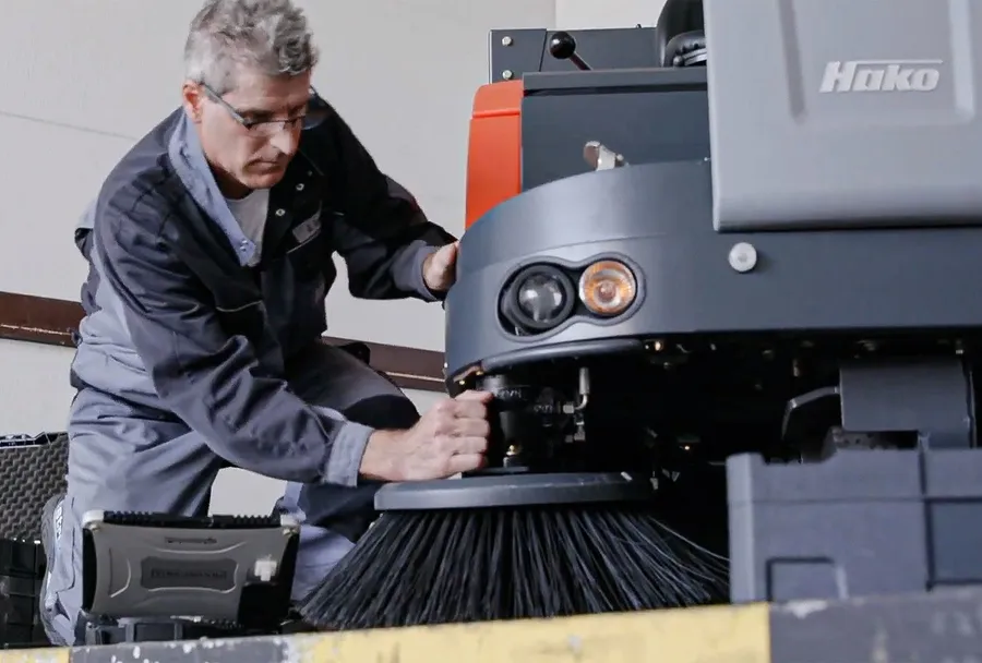 Servicetechniker der Ulrich Hofmann GmbH prüft die Kehrbürste einer Hako Kehrmaschine